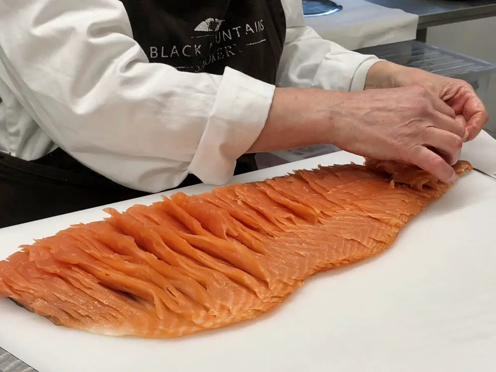 Hand slicing a side of smoked salmon