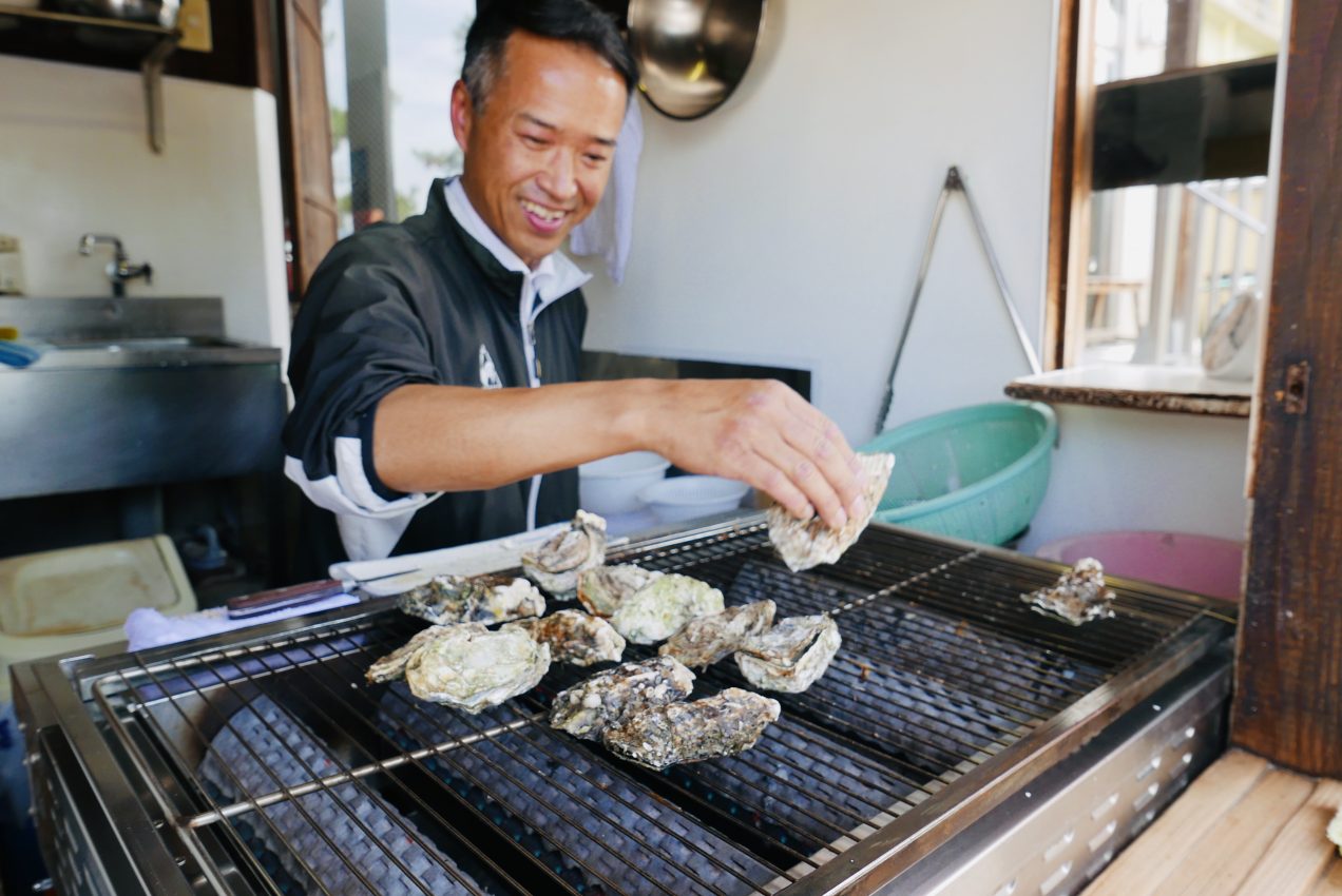 A man grilling oysters on the seafront on Miyajima Island