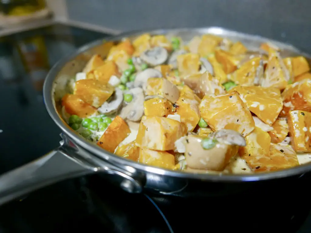 Roasted squash being fried with mushooms, garlic, peas and cream