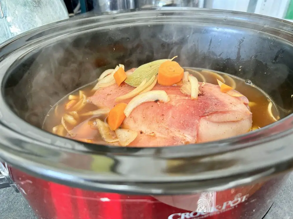 Whole pigs cheek in the slow cooker with onions, bay leaf and carrots