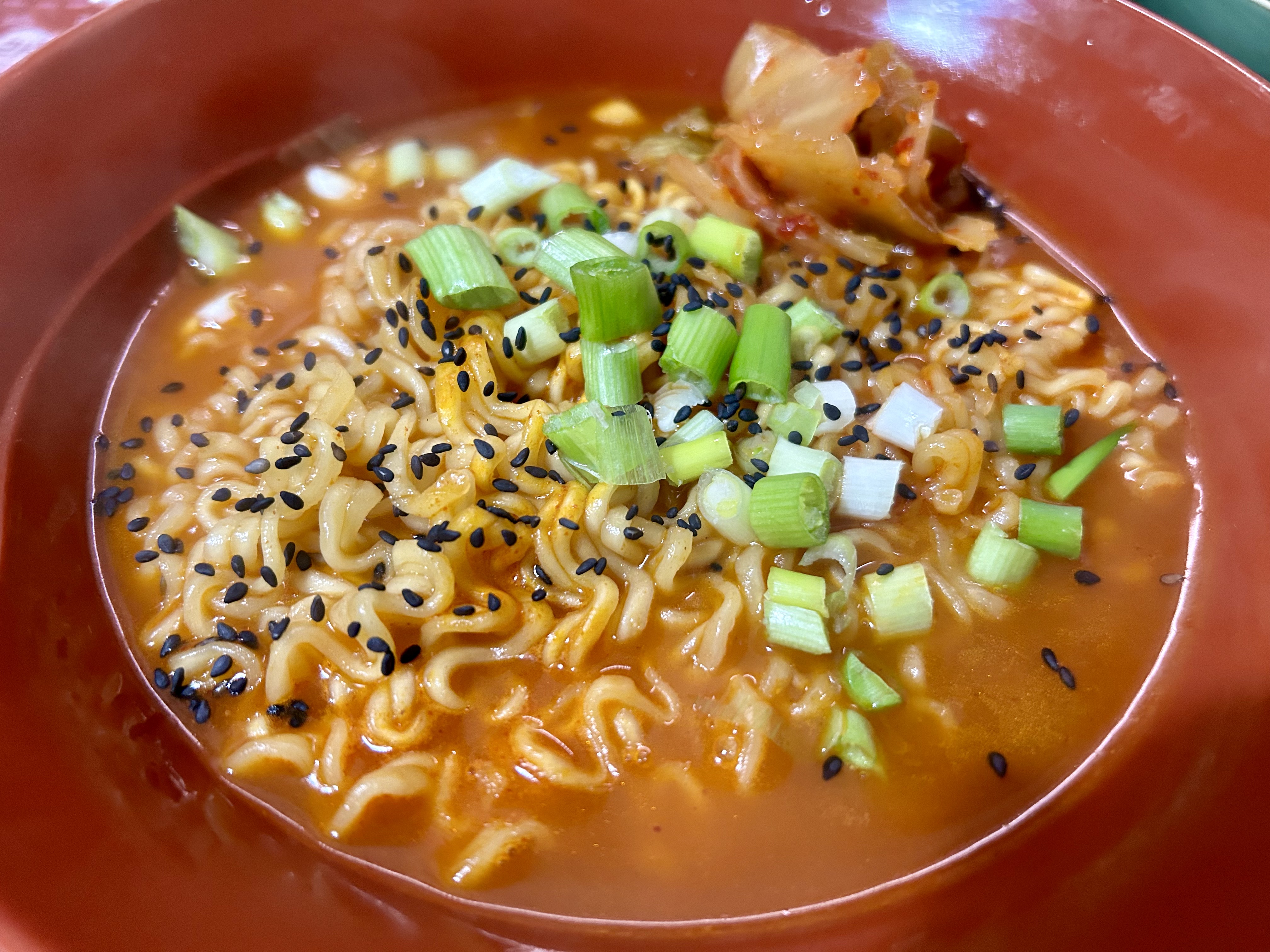 A bowl of paldo rabokki instant noodles with sesame seeds and spring onions