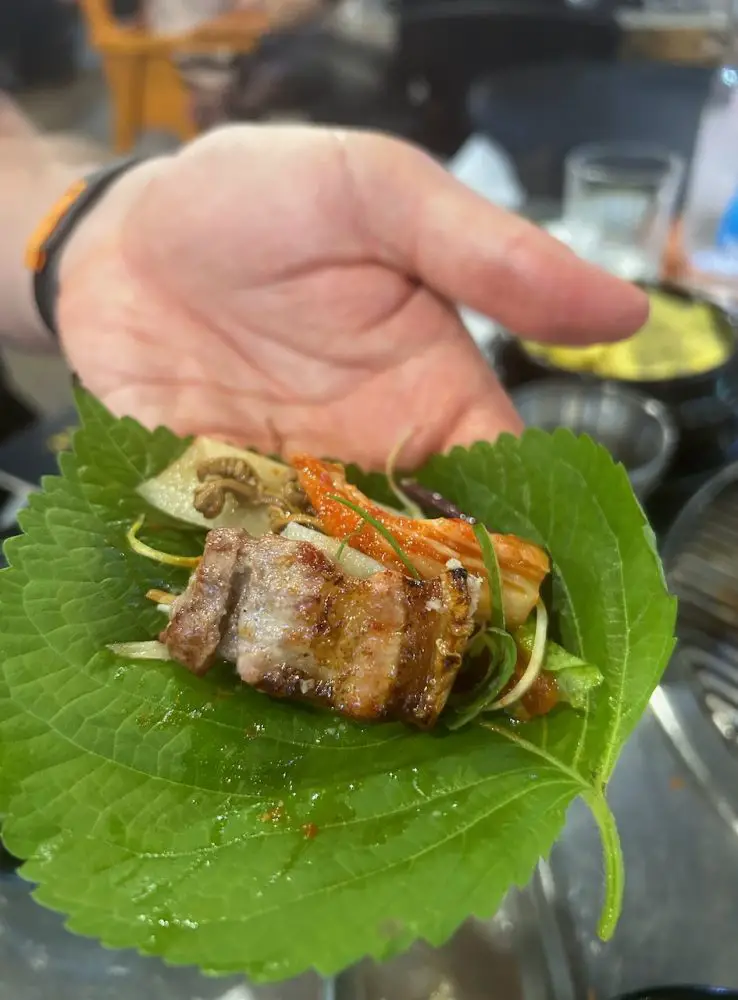 Making ssam with jeju black pork and kimchi in a perilla leaf