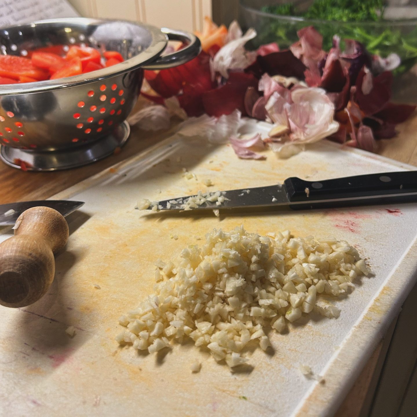 A pile of crushed garlic on a chopping board.