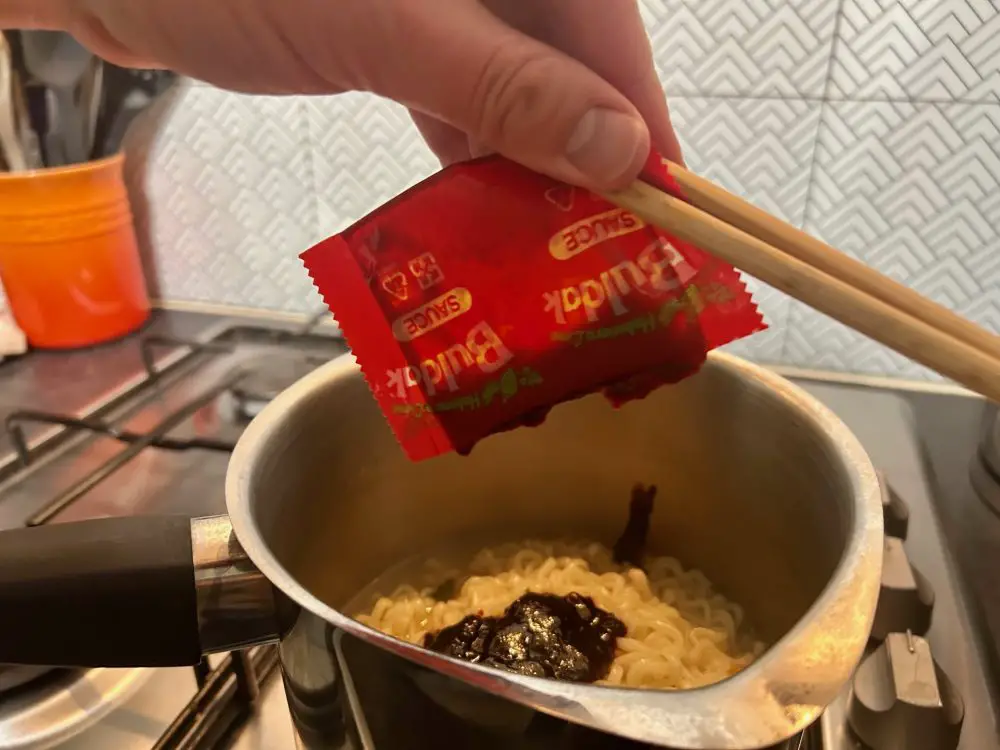 Squeezing sauce from a packet into a saucepan using chopsticks