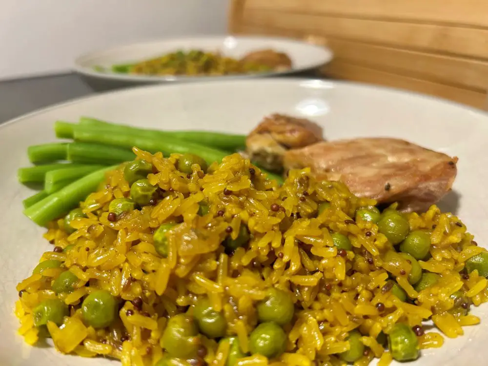 Indian style spiced rice and peas served with green beans and roast chicken thighs