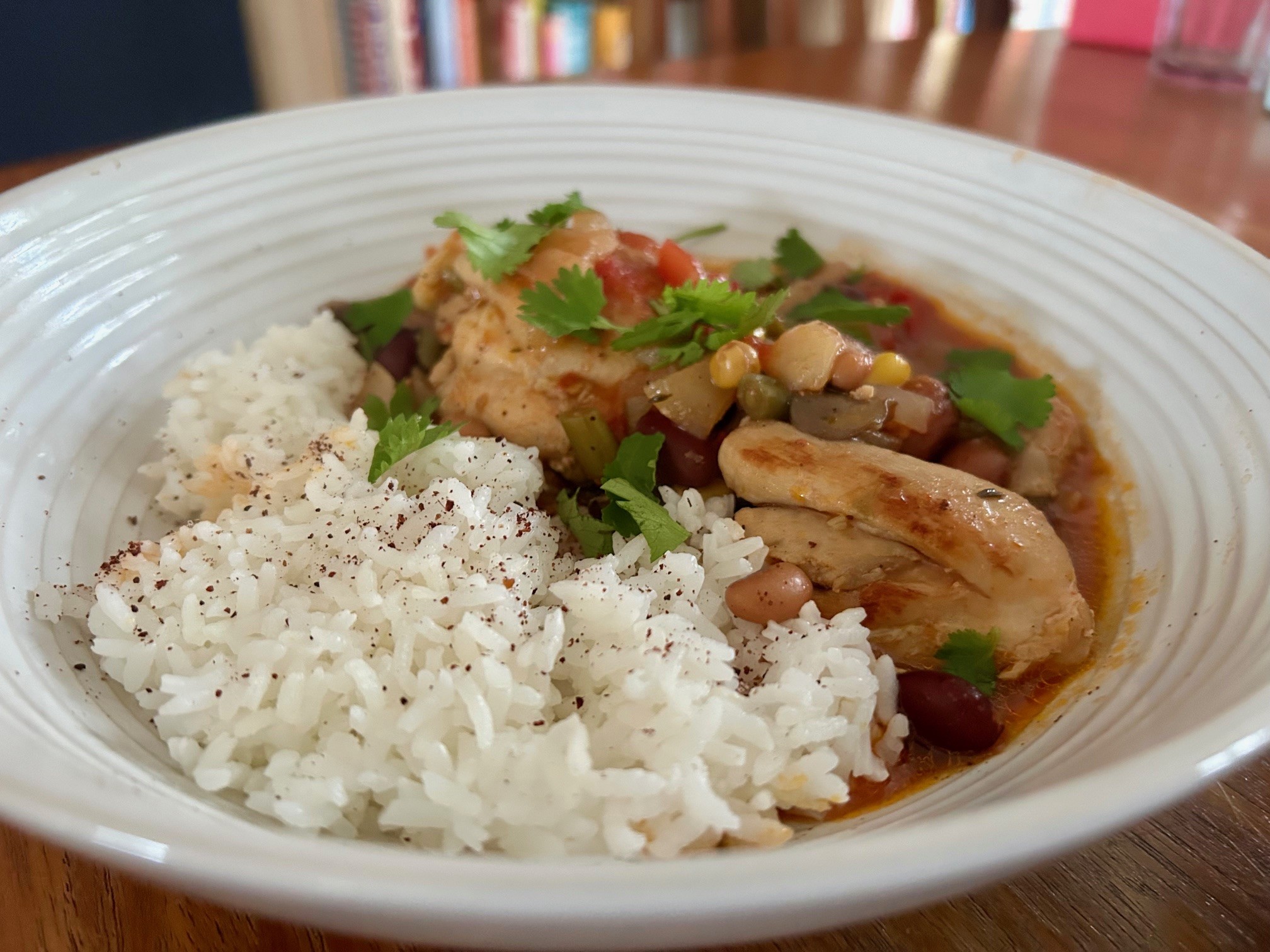 A bowl of smoky chicken and bean stew with rice seasoned with sumac and fresh coriander.