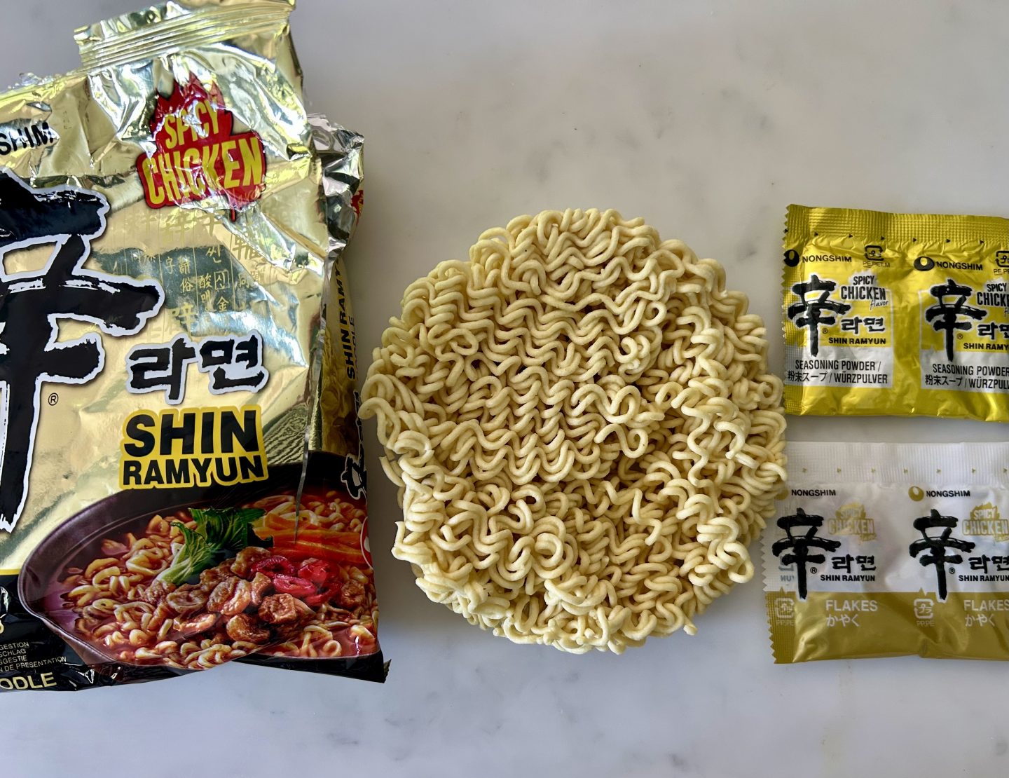 The shiny gold chicken shin ramyun packet with noodles and two packets of seasoning