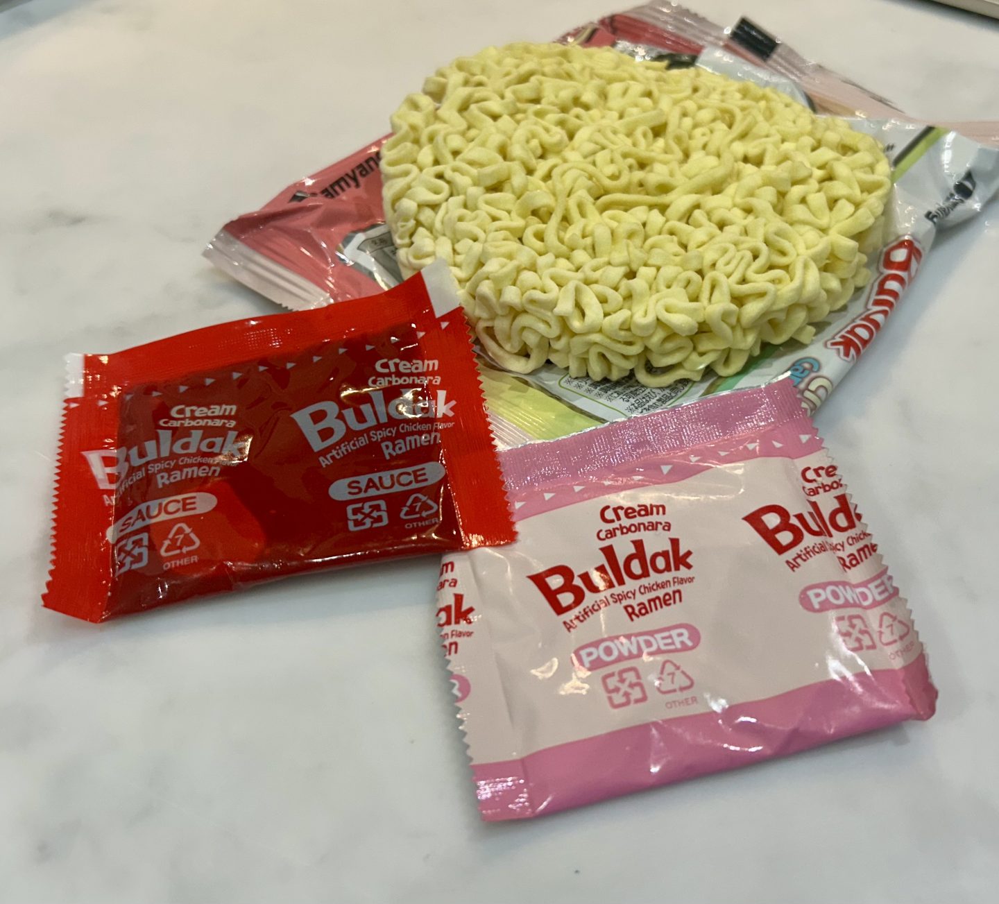 sachets and noodles inside a packet of buldak cream carbonara noodles