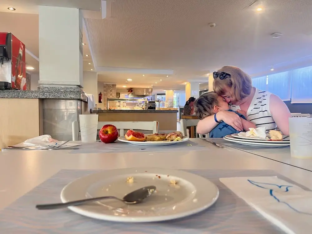 Mother cuddling her young son at a table in ar restaurant