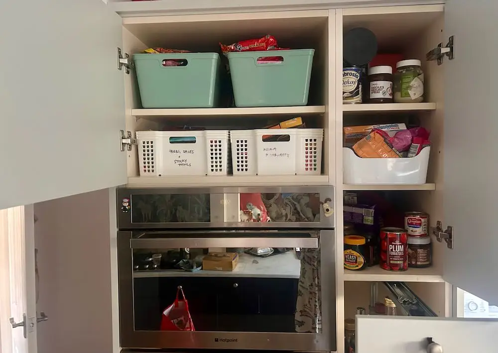 Kitchen cupboard doors open showing boxes and packets full of food