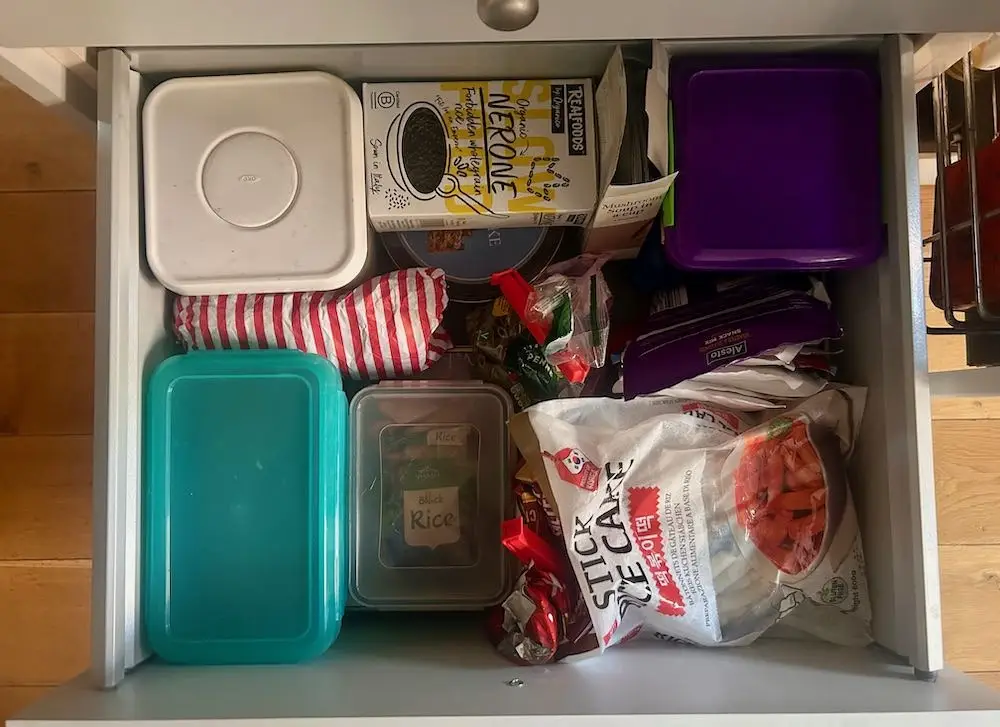 Tupperwares and packets of food crammed into a kitchen cupboard