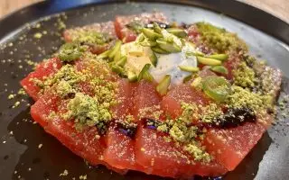 A plate of sliced watermelon, topped with whipped feta and crushed pistachio