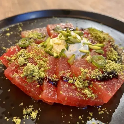 A plate of sliced watermelon, topped with whipped feta and crushed pistachio