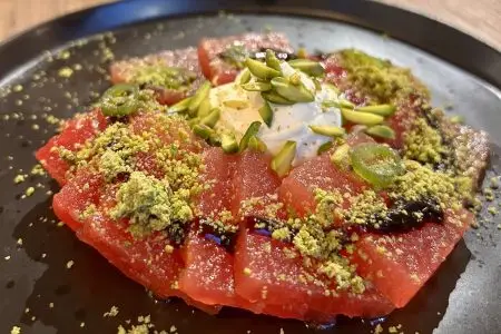 A plate of sliced watermelon, topped with whipped feta and crushed pistachio